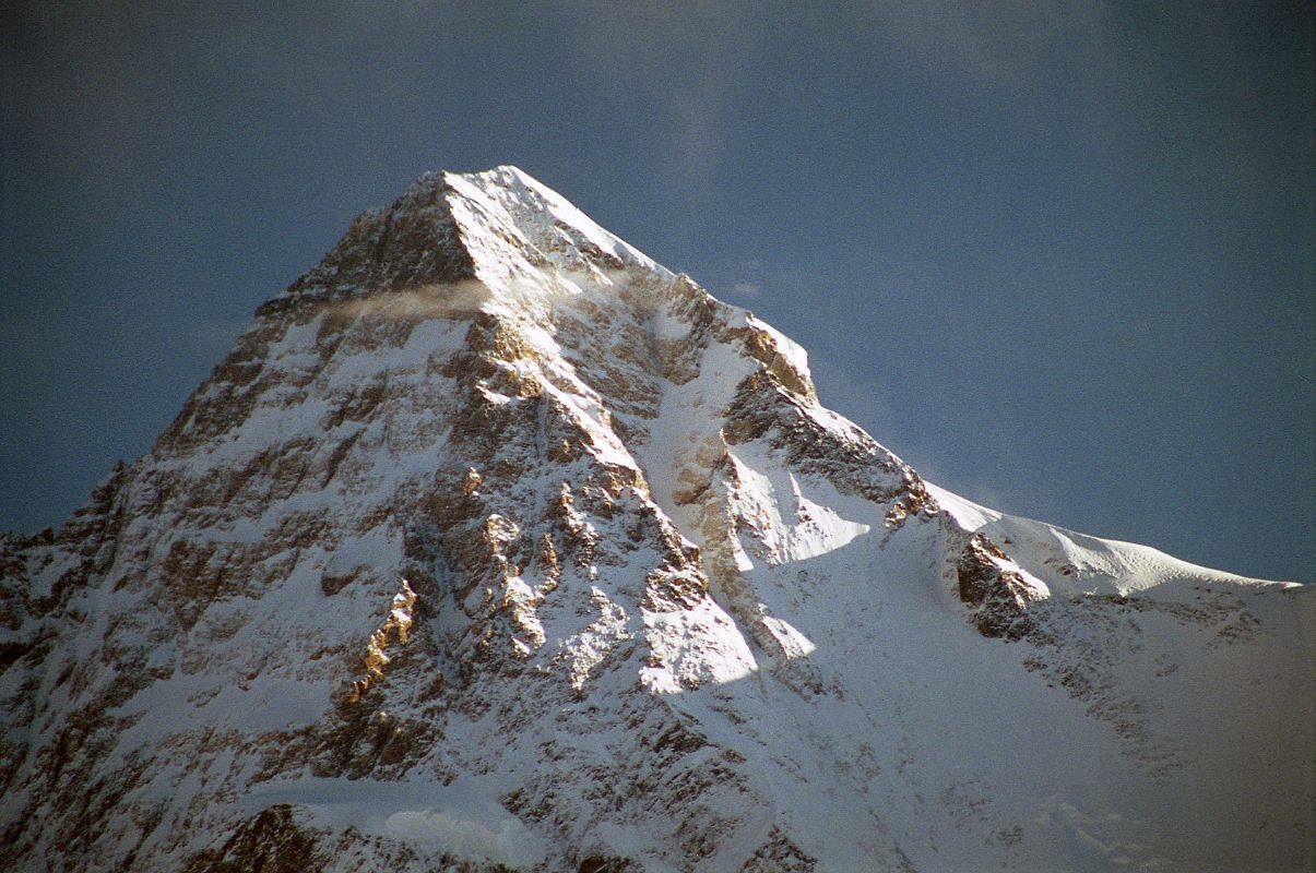 24 Sunrise On K2 Summit From Concordia The first rays of sunrise light up the K2 summit, the K2 South Face, the Great Serac, and the Shoulder, seen from Concordia. The upper part of the K2 South-South-West Ridge catches a bit of sun separating the west face in shadow from the sun descending the K2 South Face. On August 3, 1986 Wojciech Wroz, Przemyslaw Piasecki and Peter Bozik completed the first ascent of the South-South-West Ridge, called the Magic Line by Reinhold Messner. Wroz fell to his death on the descent, apparently abseiling of the end of a fixed rope.